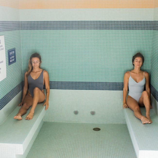 Image shows two women sitting in the steam room at MoonAcre spa
